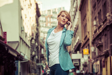 Confident mid-age woman talking on a cell phone in the street