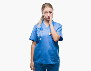 Young blonde surgeon doctor woman over isolated background thinking looking tired and bored with depression problems with crossed arms.