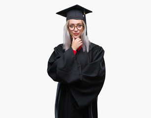 Young blonde woman wearing graduate uniform over isolated background looking confident at the camera with smile with crossed arms and hand raised on chin. Thinking positive.
