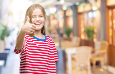 Young beautiful girl over isolated background doing happy thumbs up gesture with hand. Approving expression looking at the camera with showing success.