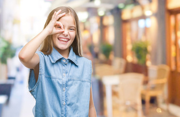 Young beautiful girl over isolated background doing ok gesture with hand smiling, eye looking through fingers with happy face.