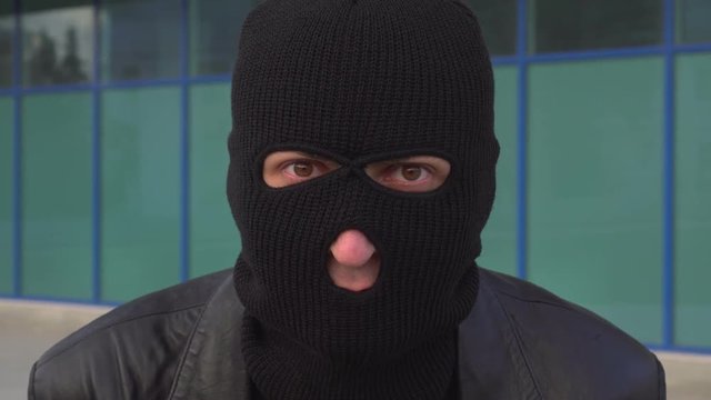 Close up portrait of criminal man thief or robber in mask looking at camera.