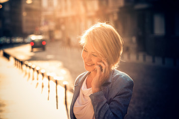 Confident mid-age woman talking on a cell phone in the street