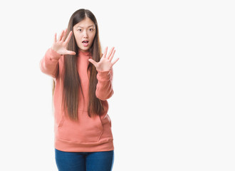 Fototapeta na wymiar Young Chinese woman over isolated background wearing sport sweathshirt afraid and terrified with fear expression stop gesture with hands, shouting in shock. Panic concept.