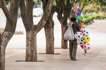 Chinese senior man street vendor selling ball and other toys.