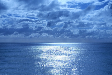 sea and sky lit by moonlight the sea is shimmering deep blue in the bottom half and the sky is cloudy