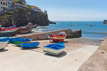 Fishing boats on the beach and in the ocean. Slipway with boats at village Camara de Lobos in Madeira, Portugal. 