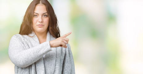 Beautiful plus size young woman wearing winter jacket over isolated background Pointing with hand finger to the side showing advertisement, serious and calm face