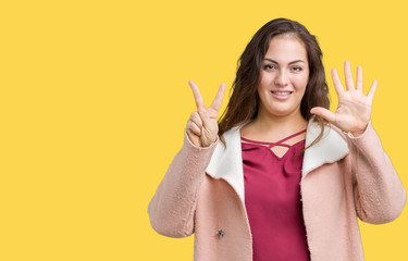 Beautiful plus size young woman wearing winter coat over isolated background showing and pointing up with fingers number seven while smiling confident and happy.
