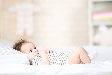 Cute baby lying with pillow on white bed