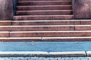 Detail of urban building entrance with aged and weathered stone stair facing the street and sidewalk in the city - Old architectural facade with steps in geometric shape and lines