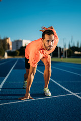 Young athlete man at starting position ready to start a race. Sprinters ready for race on race...