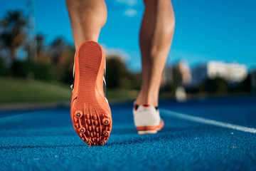 Back view of feet running man starting from start line on blue race track