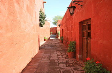 Fototapeta na wymiar Cobblestone path among red and orange color old buildings in the Monastery of Santa Catalina, Arequipa, Peru 