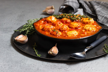 Spicy red beans, red bell pepper and meatball chili with thyme in the old frying pan. Grey concrete background. Copy space for text.