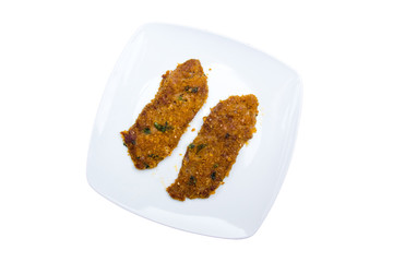 Breaded slices of meat on a plate on a white background viewed from above