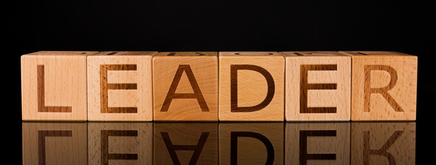 Wood cube block with word “LEADER” on Black Background. success concept, close up