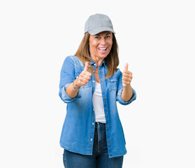 Beautiful middle age woman wearing sport cap over isolated background approving doing positive gesture with hand, thumbs up smiling and happy for success. Looking at the camera, winner gesture.