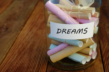 Jar with the word Dreams written on paper and attached on it. A jar with rolled papers for notes.