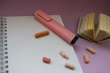 notebook and colored pencils on purple background