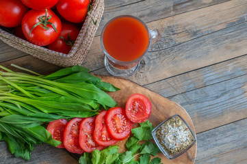 Tomato juice, a large branch of ripe red tomatoes on a wooden Board with leaves of ramsonand dill in a rustic style