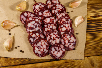 Sliced salami sausage on brown paper on wooden table