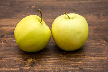 Two yellow apples on a wooden table