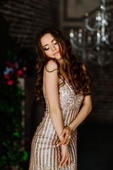 Beautiful young girl in a dress near the chandelier.