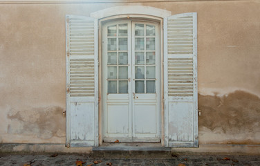 View at aged white doors with windows and shutters in old house in France