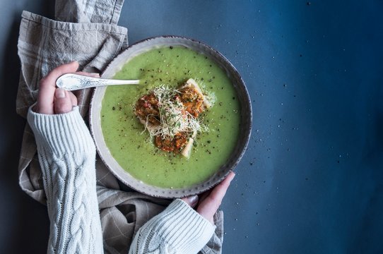Overhead view of woman's hand holding bowl of creamy leek soup