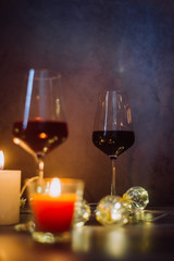 Holidays composition made of glass of red wine, candles and garlands on a dark background