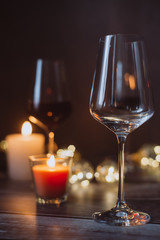 Holidays composition made of glass of red wine, candles and garlands on a dark background
