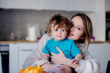 Happy white mother and son with pumpkin. Domestic image at kitchen