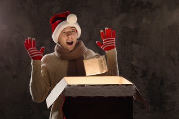 Christmas gift concept. Man in santa hat bring gift for you. Attractive man hold box.  Christmas and new year holiday celebration. Happy surprised man move up gift with magic