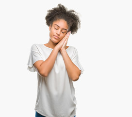 Fototapeta na wymiar Young afro american woman over isolated background sleeping tired dreaming and posing with hands together while smiling with closed eyes.