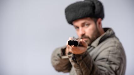 Hunter with horizontal double-barreled shotgun in hands, rifle is directed forward, retro style, studio shot