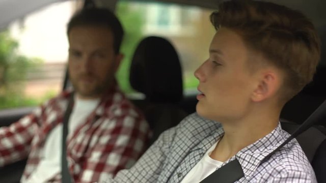 Male instructor teaching teenager to drive automobile, safety rules, close-up