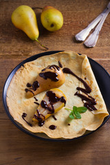 Crepes with baked pear and chocolate. Thin pancakes with baked pear and chocolate. vertical