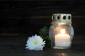 Condolence card with burning grave candle and chrysanthemum flower on wooden background