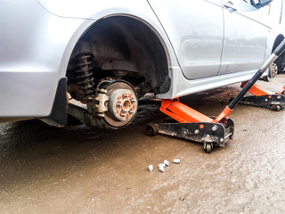 The car is at the tire shop. Under the jack the car in car-care center. The car with the removed wheel