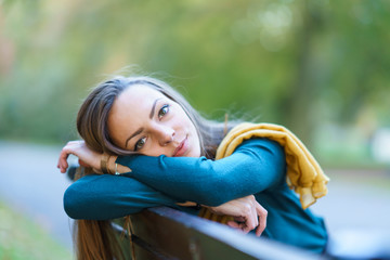 Smiling beautiful woman sitting on bench in park