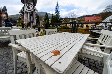 Autumn leaf on the wet table of the street cafe.