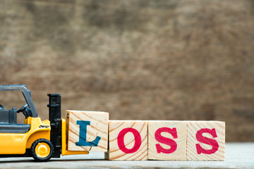 Yellow toy forklift hold letter block l to complete word loss on wood background