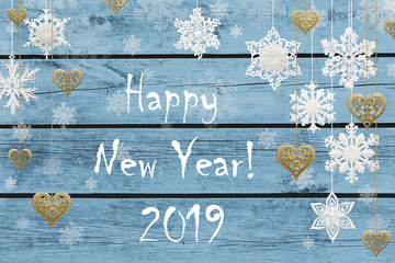 Happy New Year!  New Year decorations: snowflakes and golden hearts on blue wooden background.