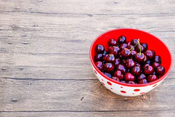 Berries of a sweet cherry on a wooden background in a plastic cup. Ripe red sweet cherry.