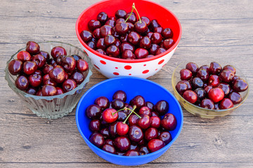 Berries of a sweet cherry on a wooden background in a plastic cup. Ripe red sweet cherry.