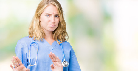 Beautiful young doctor woman wearing medical uniform over isolated background disgusted expression,...