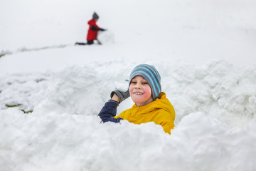 Fototapeta na wymiar boy playing in a snow fort. snowball game. The concept of winter fun