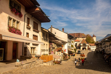 Gruyere medieval city in Switzerland. Old buildings, castle, vendors and blue sky