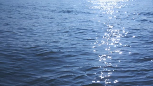 Slow motion shot of sparkling sunlight reflecting off water waves.